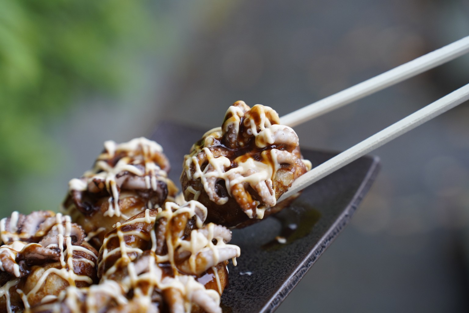 イイダコ入りたこ焼きを箸で持ち上げた写真